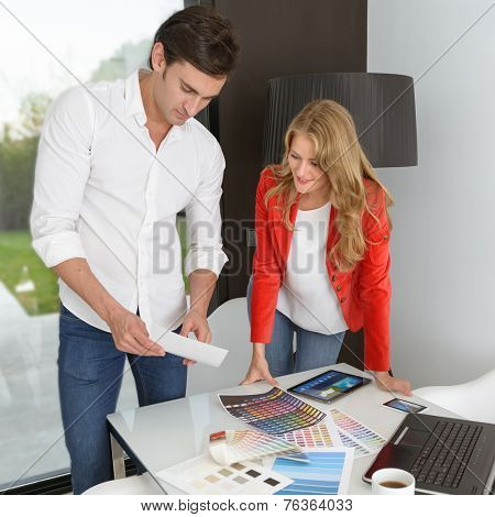 Man and woman in an office surrounded by color charts, material samples and technology