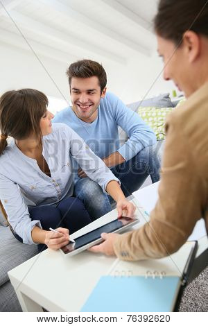 Young couple signing financial contrat on digital tablet