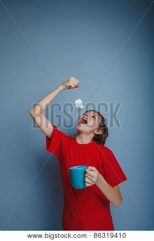 boy teenager European appearance in a red shirt holds a blue cup
