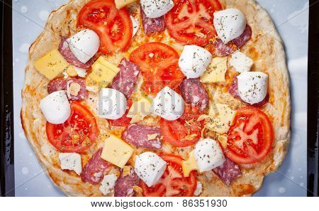 Raw pizza dough with mozzarella and proscuitto on top