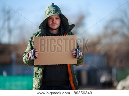 Homeless person with blanck cardboard. Focused on cardboard