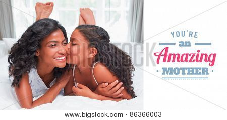 mothers day greeting against pretty woman lying on bed with her daughter kissing cheek