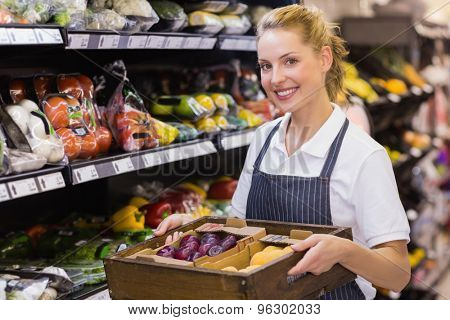Portrait of a smiling blonde worker holding a box with vegetables in supermarker