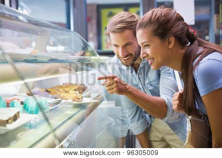 Young happy couple choosing cake in the cafe
