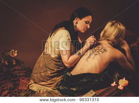 Drawing process of henna menhdi ornament on woman's back 