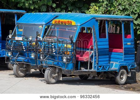 Auto rickshaw taxis on a road.