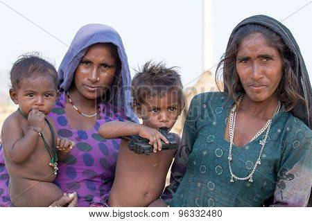beggar women and children begs for money from a passerby in Pushkar.
