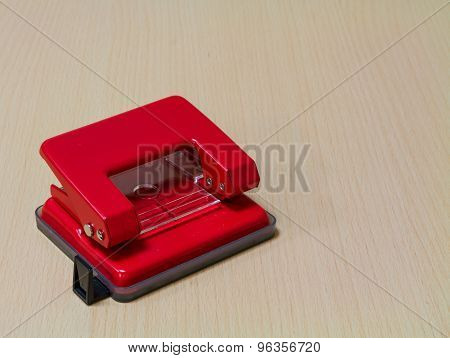 Red  paper hole puncher On Wooden Background.