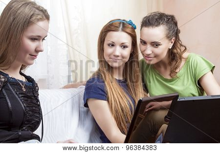 Lifesrtyle Concept. Portrait Of Three Young Caucasian Girlfriends With Laptops Sitting On Couch. Ind