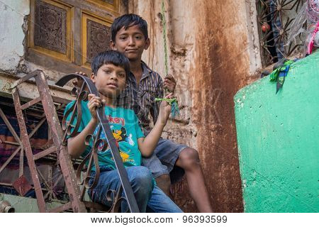 MUMBAI, INDIA - 12 JANUARY 2015: Two young boys sit on high stairs in front of home in Dharavi slum. Dharavi is one of the largest slums in the world.