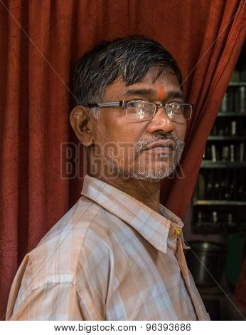 MUMBAI, INDIA - 12 JANUARY 2015: Elderly Indian man with glasses and bindi stands in doorway of home.