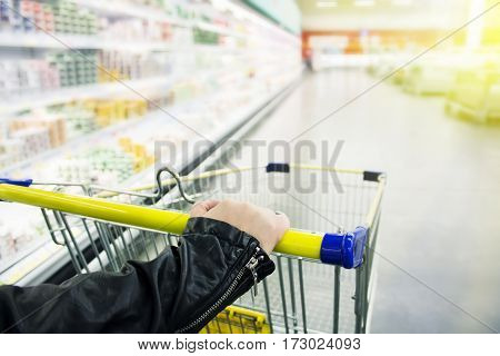 Cart at the grocery store. Girl holding a cart and chooses products.