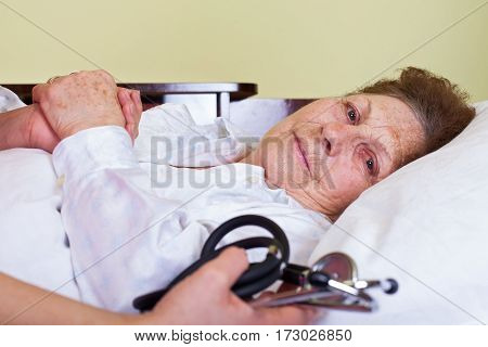 Picture of a bed ridden elderly woman with her care holding a stethoscope