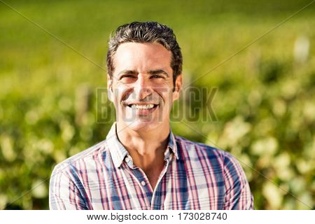 Portrait of smiling male vintner standing in vineyard