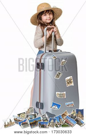 Long haired little girl with straw hat is standing and leaning on a suitcase. Photos of the sights of Prague (Czech Republic) flies around the suitcase. All is on the white background. Vertically.