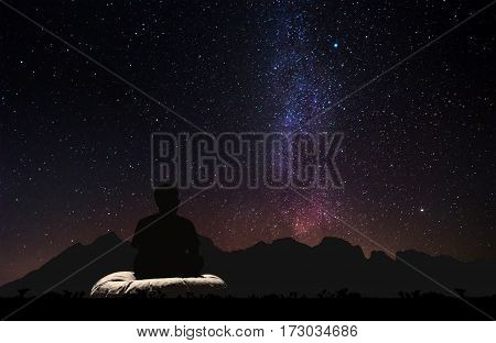 Silhouette a man sitting relaxing under the sky with milky way and stars at night