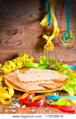 Carnival pastry with confetti on wooden table.