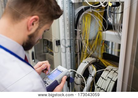 Technician using digital cable analyzer in server room