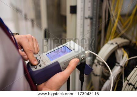 Mid section of technician using digital cable analyzer in server room