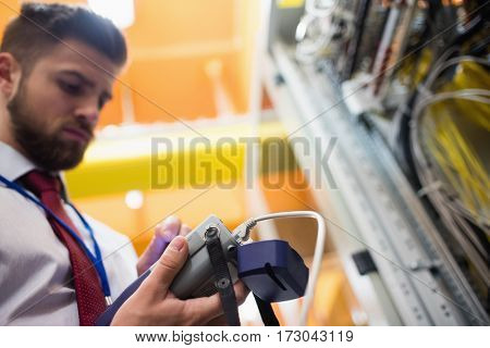 Technician using digital cable analyzer in server room