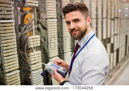 Portrait of technician using digital cable analyzer in server room