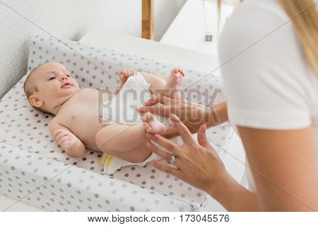 Mother changing the diaper of her baby at home