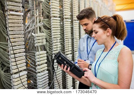 Technicians using digital cable analyzer in server room