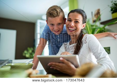 Mother and son using digital tablet in the living room at home