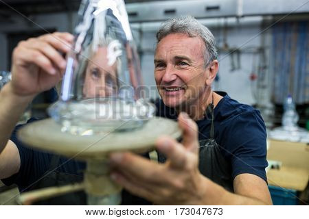 Glassblower and a colleague examining glassware at glassblowing factory