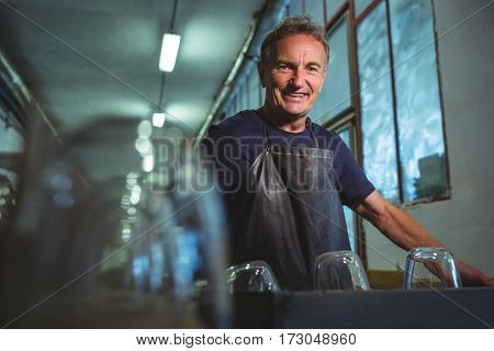 Portrait of smiling glassblower standing in glass blowing factory