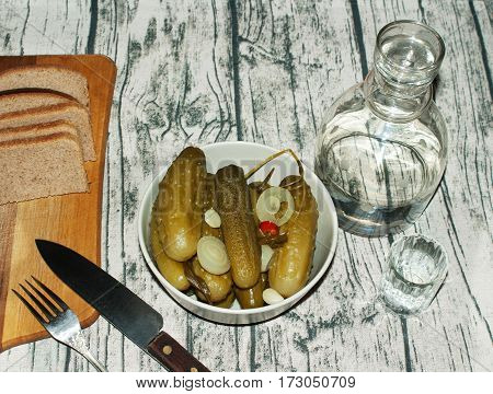 Pickled cucumbers with onion and red pepper bread carafe and glass of vodka fork knife