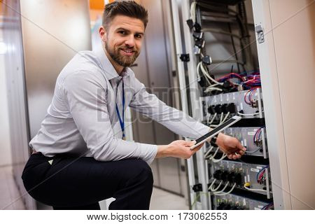 Portrait of technician using digital tablet while analyzing server in server room