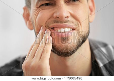 Handsome young man suffering from toothache, closeup