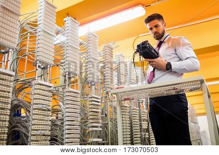 Technician using digital cable analyzer in server room