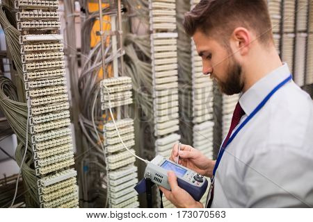Technician using digital cable analyzer in server room