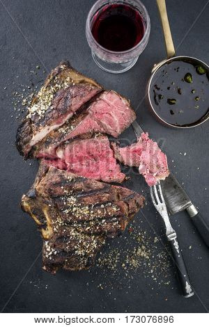 Barbecue dry aged Rib of Beef with sauce as close-up on a black slate