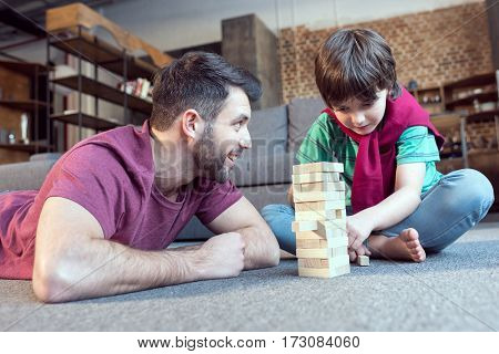 low angle view of father looking at son playing jenga game