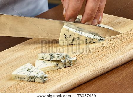cutting cheese on a wooden cooking board male hands chef