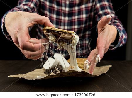 Womans Hands Pick Up Gooey Marshmallow Smore with sticky fluff