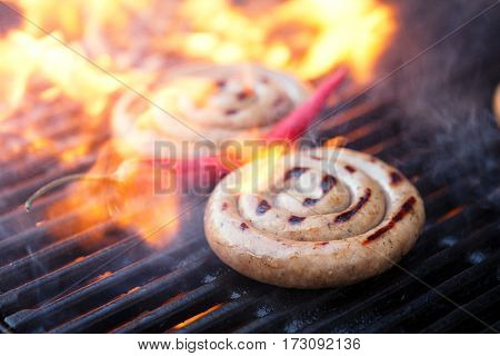 cumberland sausage, spiral pork sausage on bbq grill with flame, homemade