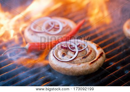 cumberland sausage, spiral pork sausage on bbq grill with flame, homemade