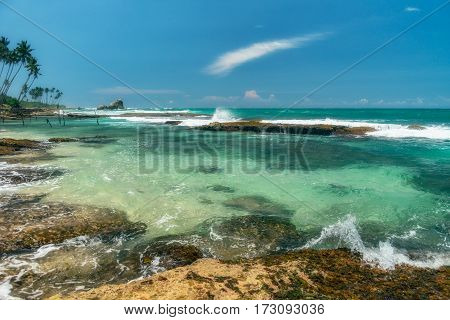 Sunny beach near Koggala - Sri Lanka The area famous for its distinct stilt fishermen, who erect a single pole in the chest-deep water on the beach, just few meters off-shore. Splittoned, vivid image.