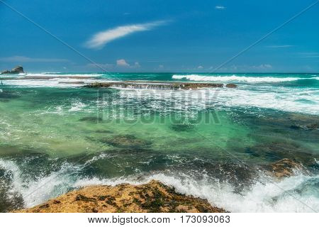 Sunny beach near Koggala - Sri Lanka The area famous for its distinct stilt fishermen, who erect a single pole in the chest-deep water on the beach, just few meters off-shore. Splittoned, vivid image.