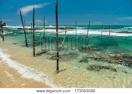 Sunny beach near Koggala - Sri Lanka The area famous for its distinct stilt fishermen, who erect a single pole in the chest-deep water on the beach, just few meters off-shore. Splittoned, vivid image.