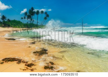 Sunny beach near Koggala - Sri Lanka The area famous for its distinct stilt fishermen, who erect a single pole in the chest-deep water on the beach, just few meters off-shore. Splittoned, vivid image.