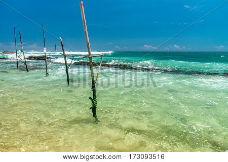 Sunny beach near Koggala - Sri Lanka The area famous for its distinct stilt fishermen, who erect a single pole in the chest-deep water on the beach, just few meters off-shore. Splittoned, vivid image.