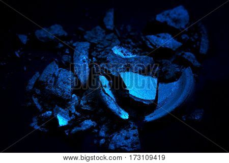Crushed eye shadow isolated on black background vith spooth light. Beauty and fassion style.Eye shadow of blue color.