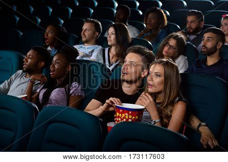 Best date entertainment. Portrait of a surprised young couple enjoying a movie at the cinema on their date night