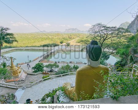 View from yathaypyan cave on surrounding landscape with back of buddha statue lake and surrounding hills and mountains