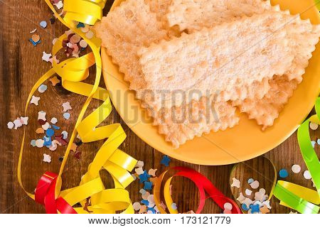 Carnival pastry with confetti on wooden table.